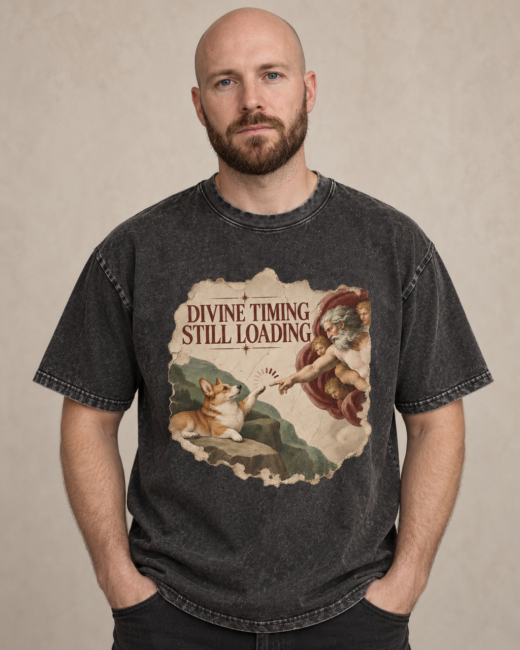 Adult model wears Black Corgi Divine Timing Still Loading Creation Parody washed T-shirt in a warm studio portrait