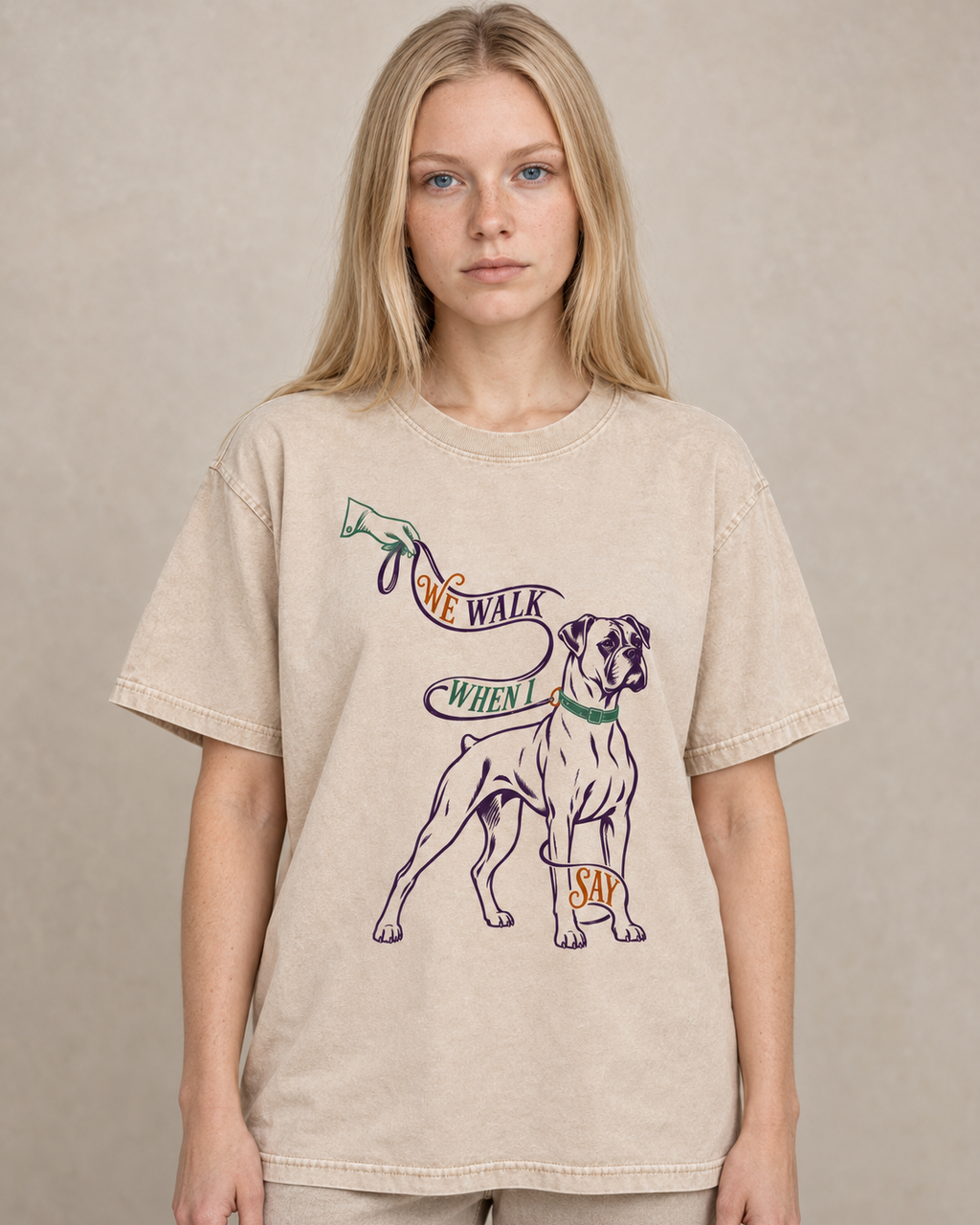 Adult model wears Apricot Boxer We Walk When I Say Leash washed T-shirt in a warm studio portrait