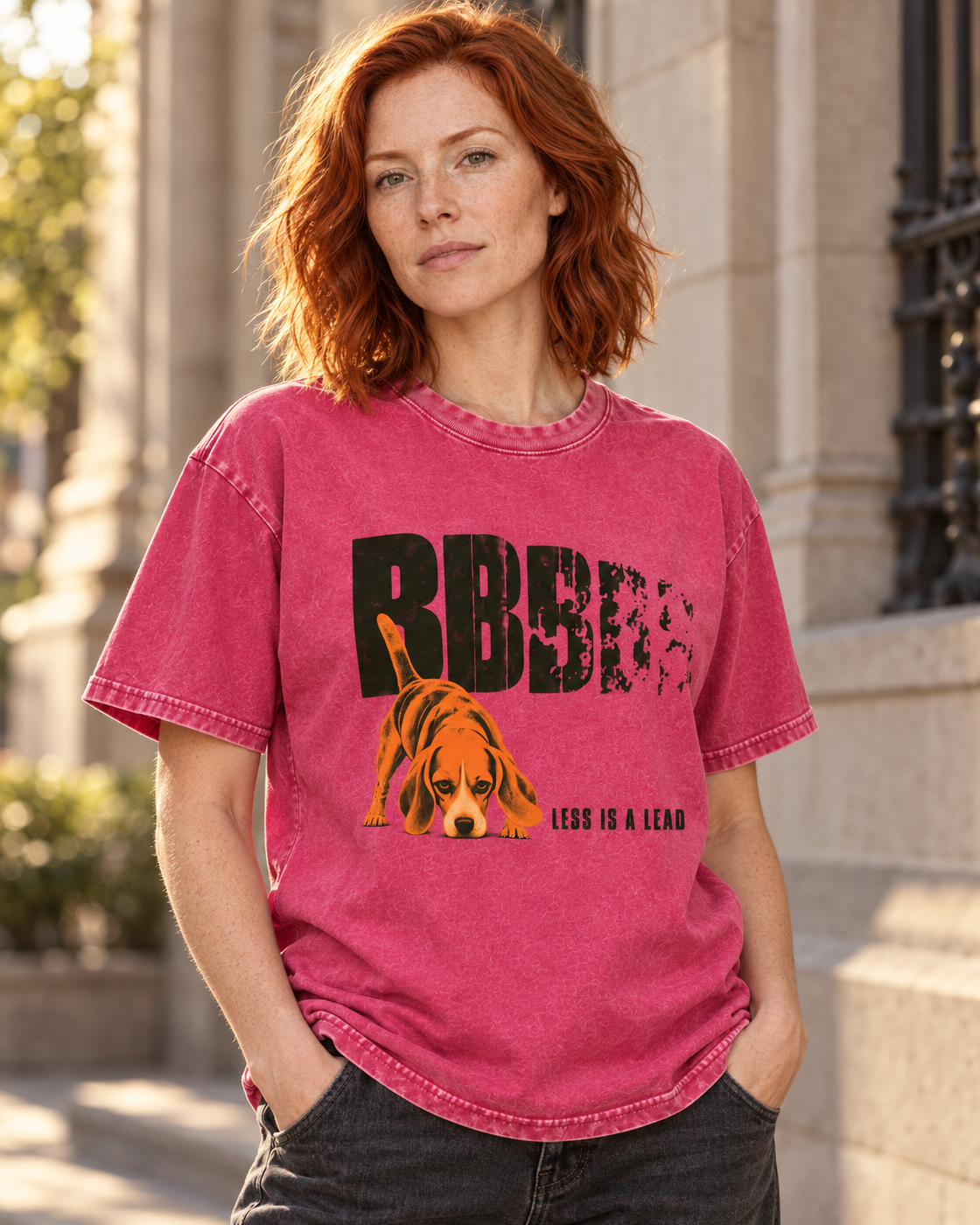 Adult model wears Fuchsia Beagle Less Is A Lead Tracking Dog washed T-shirt in a three-quarter street portrait