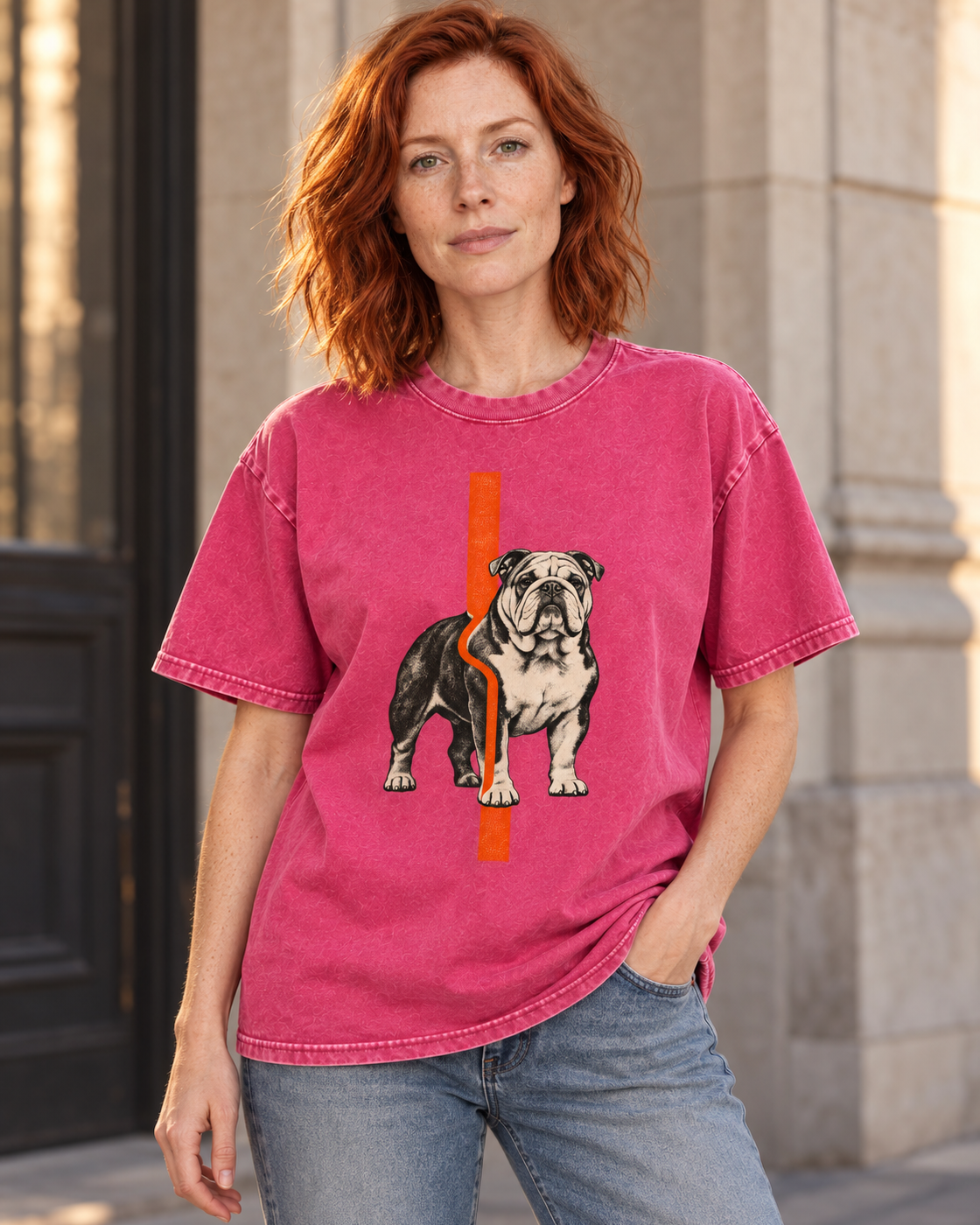 Adult model wears Fuchsia English Bulldog Orange Offset Line washed T-shirt in a three-quarter street portrait