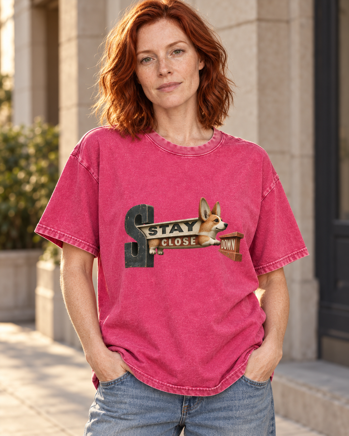 Adult model wears Fuchsia Corgi Stay Close Down Sign washed T-shirt in a three-quarter street portrait
