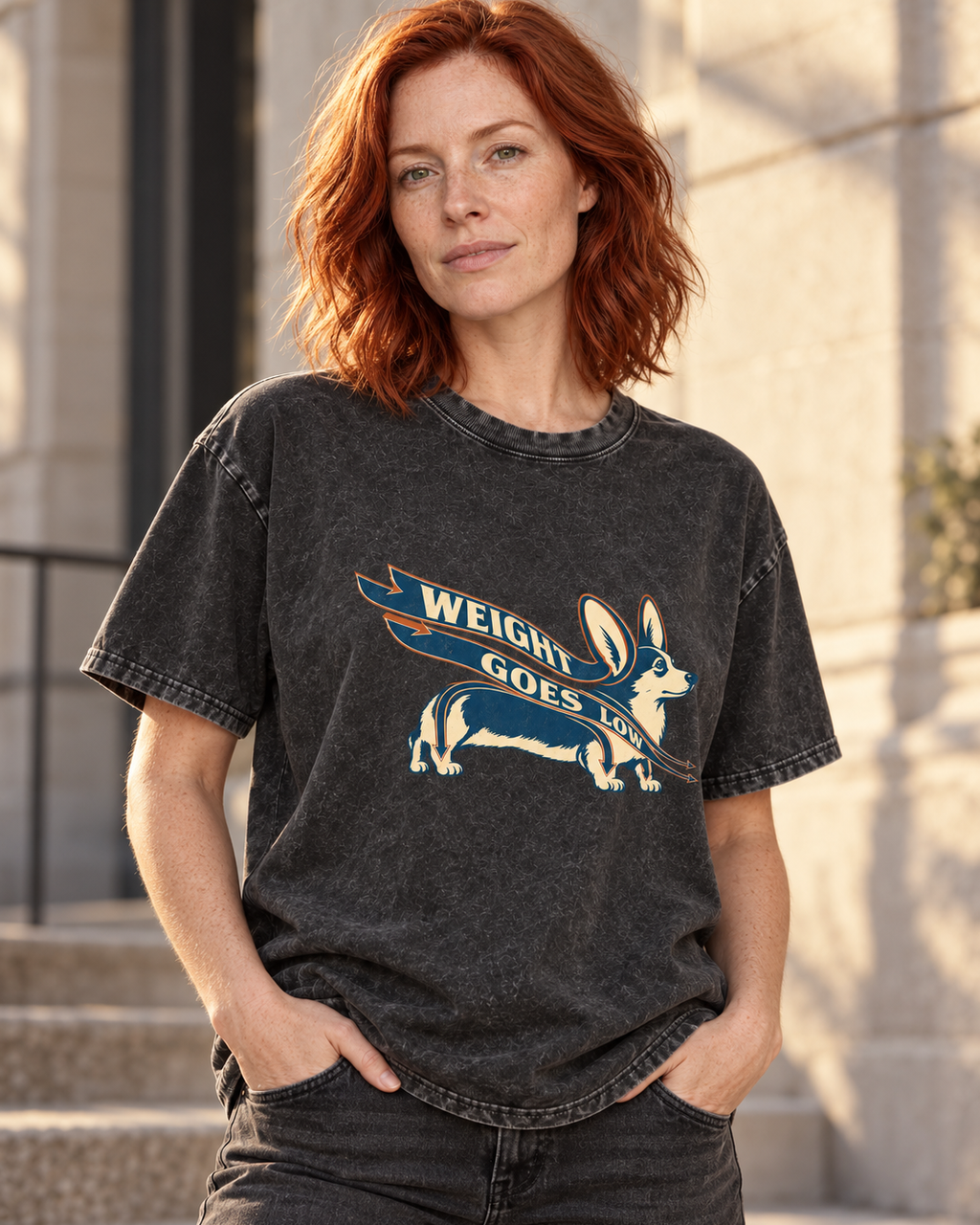 Adult model wears Black Corgi Weight Goes Low Ribbon Arrow washed T-shirt in a three-quarter street portrait