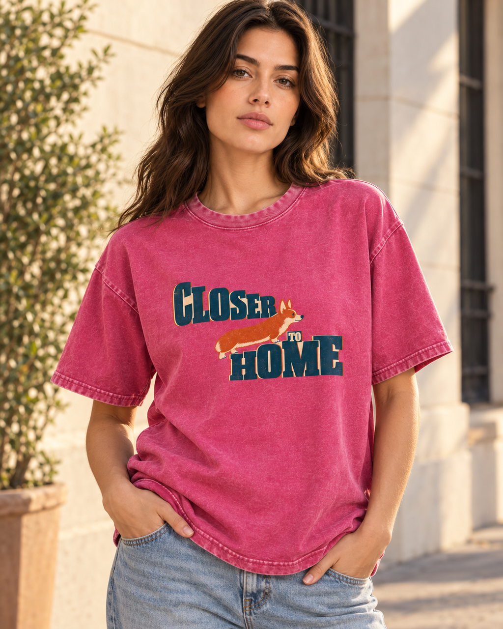 Adult model wears Fuchsia Corgi Closer to Home Typographic washed T-shirt in a three-quarter street portrait