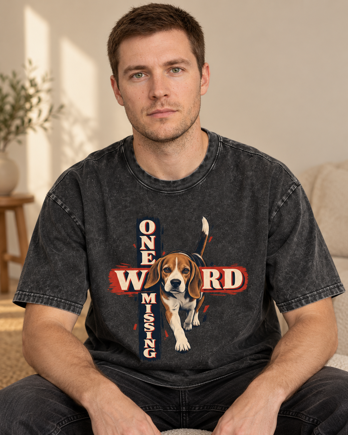 Adult model wears Black Beagle One Word Missing washed T-shirt in a seated indoor portrait