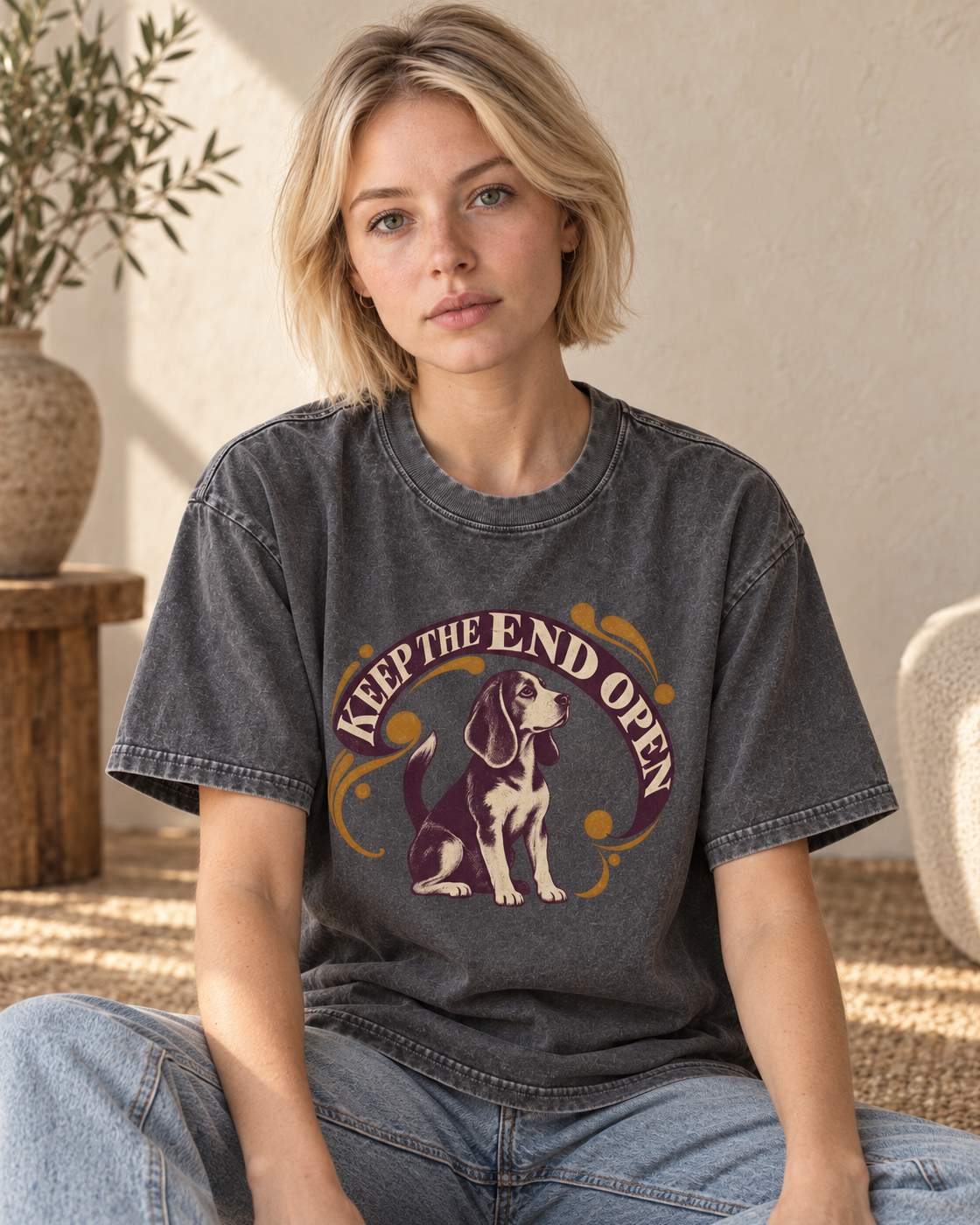 Adult model wears Gray Beagle Keep The End Open Ornamental washed T-shirt in a seated indoor portrait