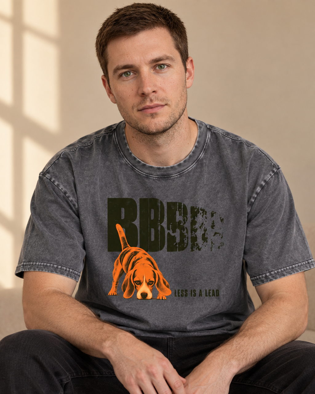 Adult model wears Gray Beagle Less Is A Lead Tracking Dog washed T-shirt in a seated indoor portrait