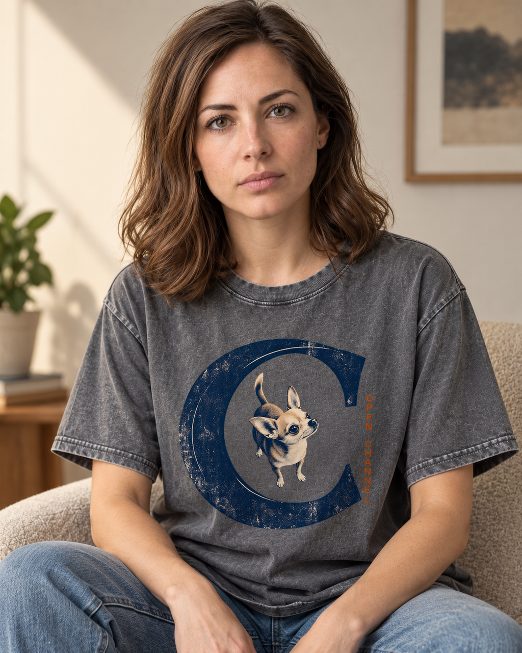 Adult model wears Gray Chihuahua Open Channel washed T-shirt in a seated indoor portrait