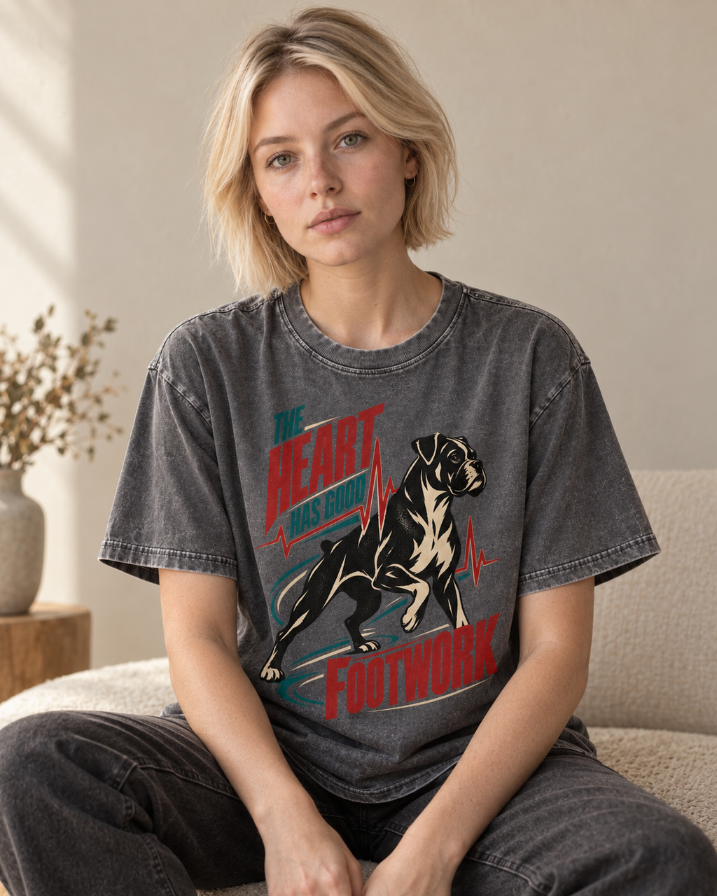 Adult model wears Gray Boxer The Heart Has Good Footwork ECG Motion washed T-shirt in a seated indoor portrait
