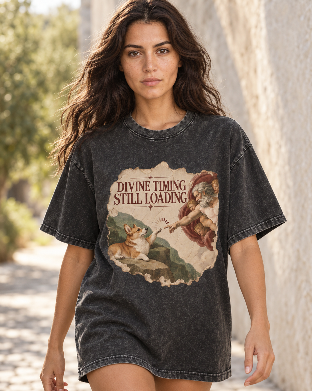 Adult model wears Black Corgi Divine Timing Still Loading Creation Parody washed T-shirt in a natural walking portrait