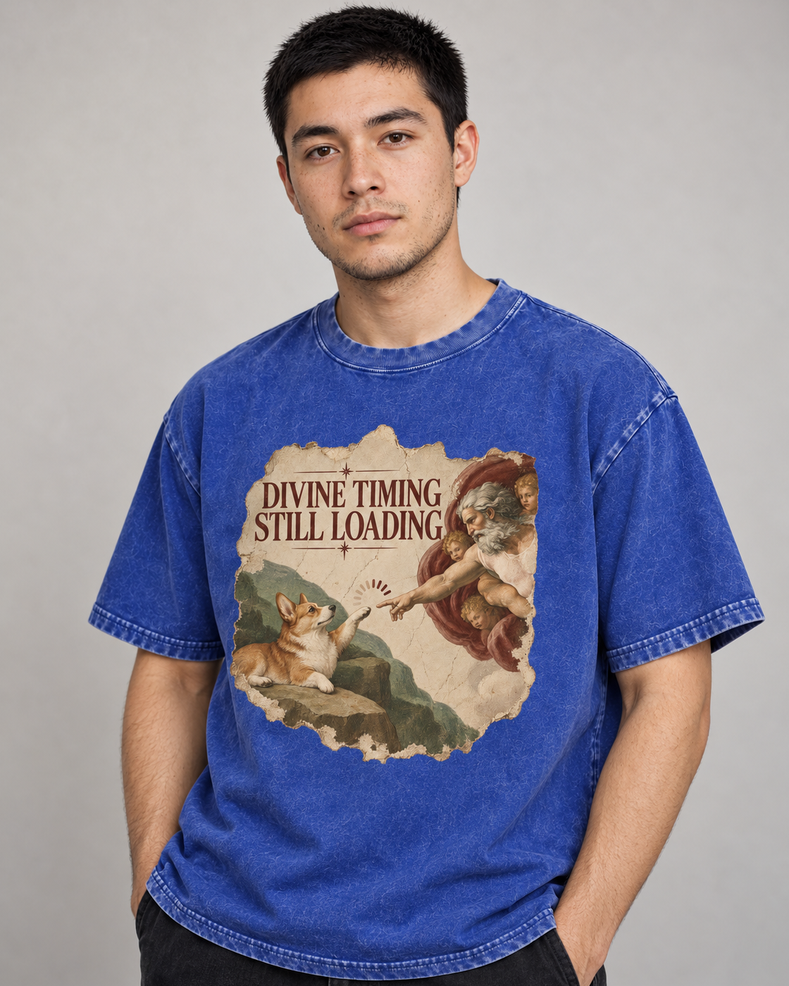Adult model wears Royal Blue Corgi Divine Timing Still Loading Creation Parody washed T-shirt in a side-angle editorial port