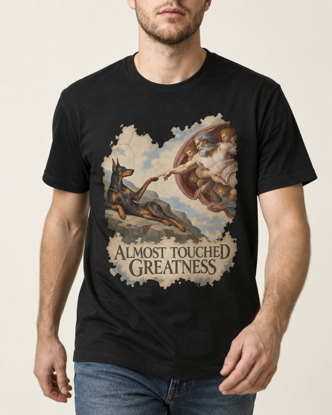 Doberman Almost Touched Greatness Creation Scene Graphic T-Shirt in Black, worn by a model, front view