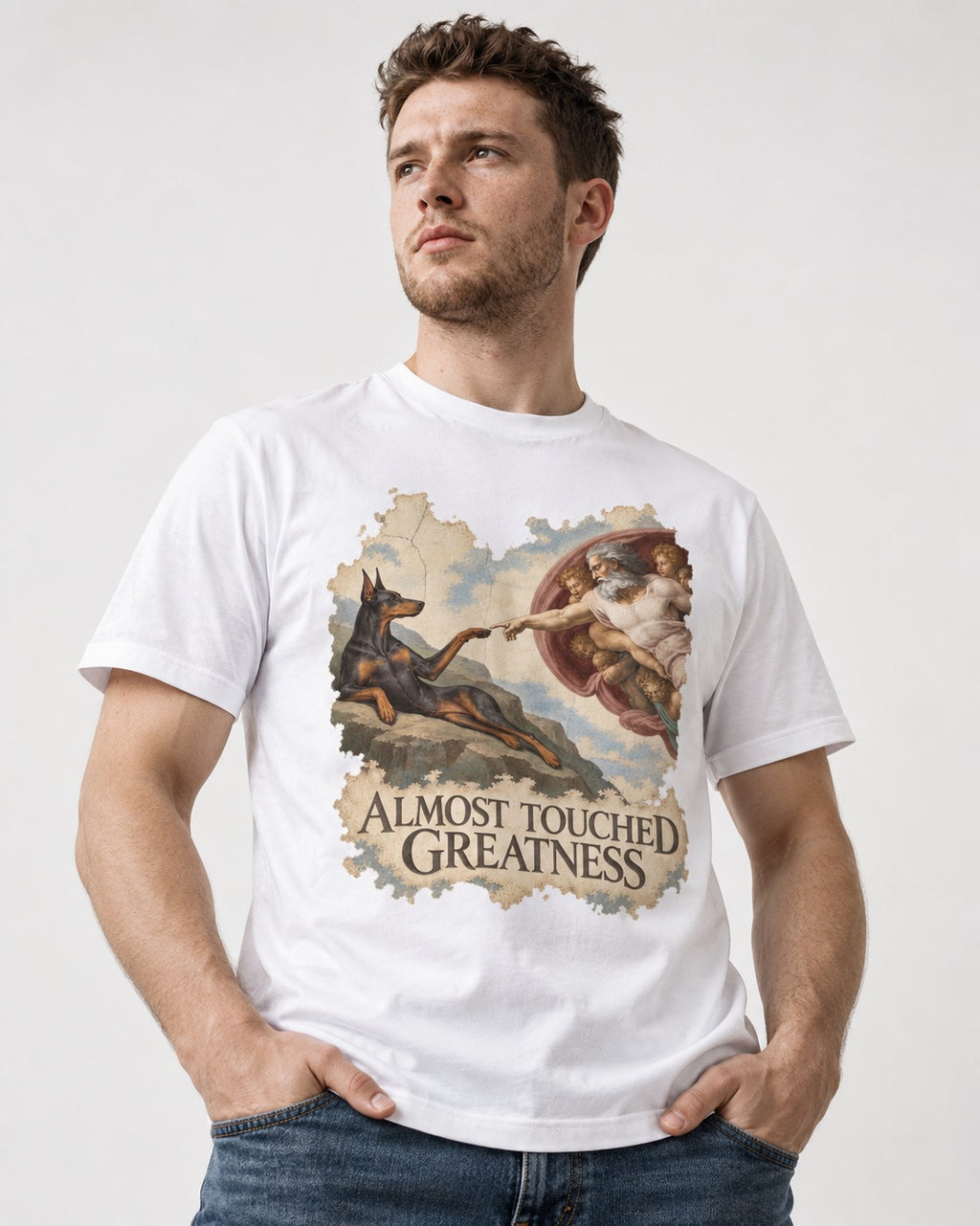 Doberman Almost Touched Greatness Creation Scene Graphic T-Shirt in White, worn by a model