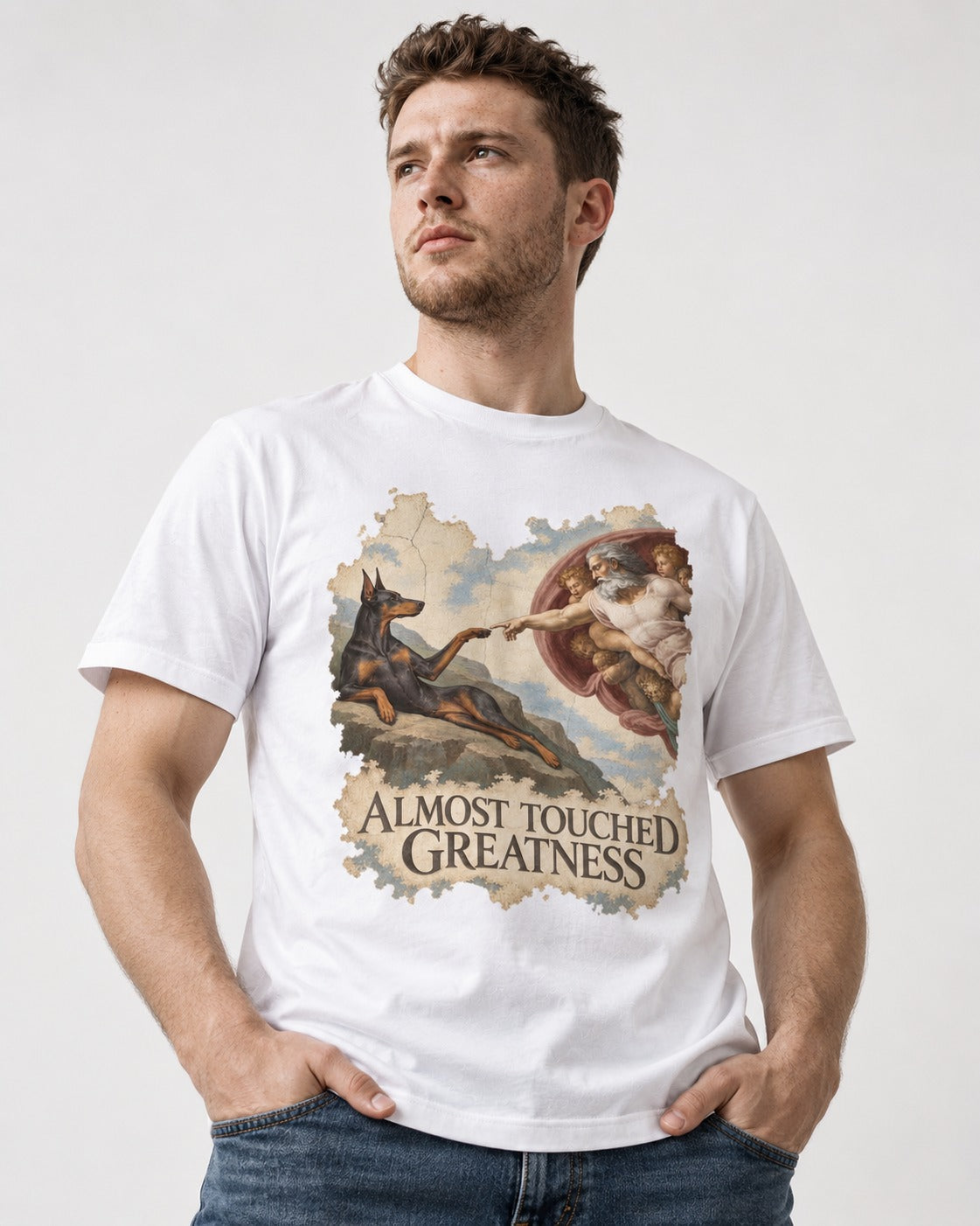 Doberman Almost Touched Greatness Creation Scene Graphic T-Shirt in White, worn by a model