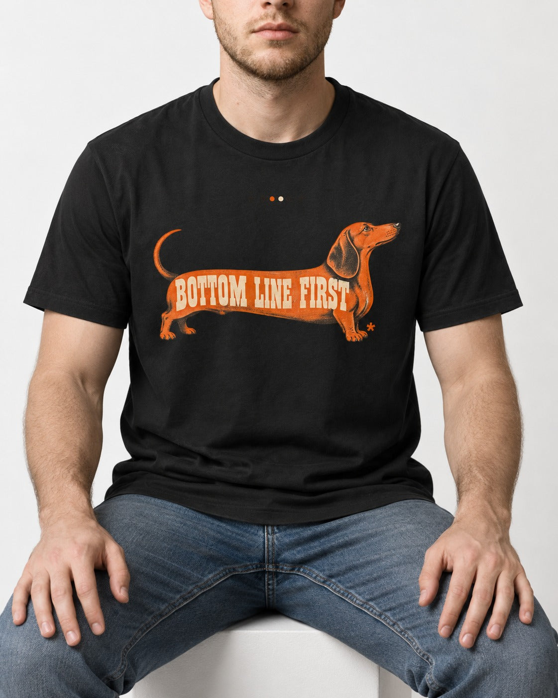 Dachshund Bottom Line First Body Lettering Graphic T-Shirt in Black, worn by a seated model