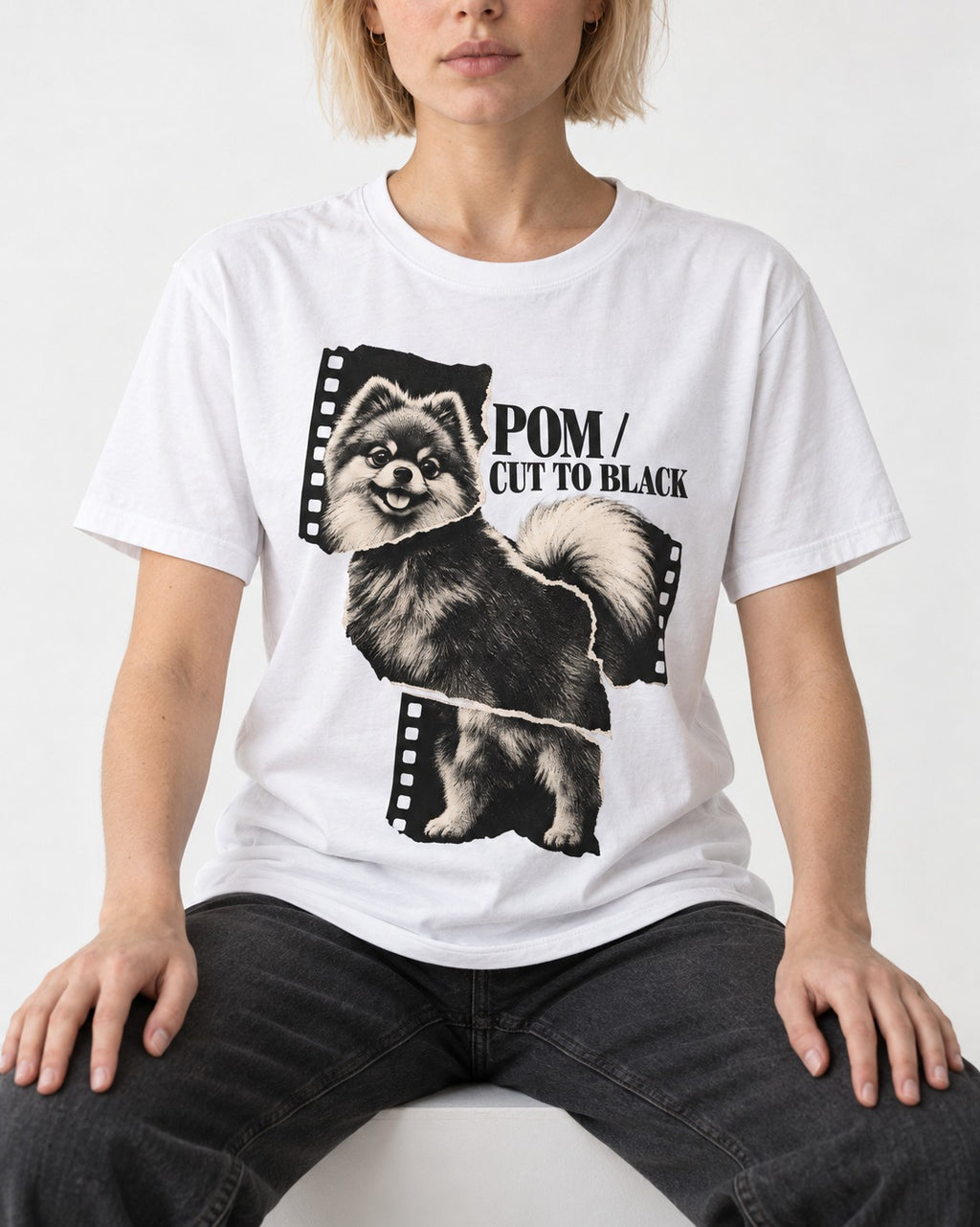 Pomeranian Cut to Black T-Shirt in White, worn by a seated model