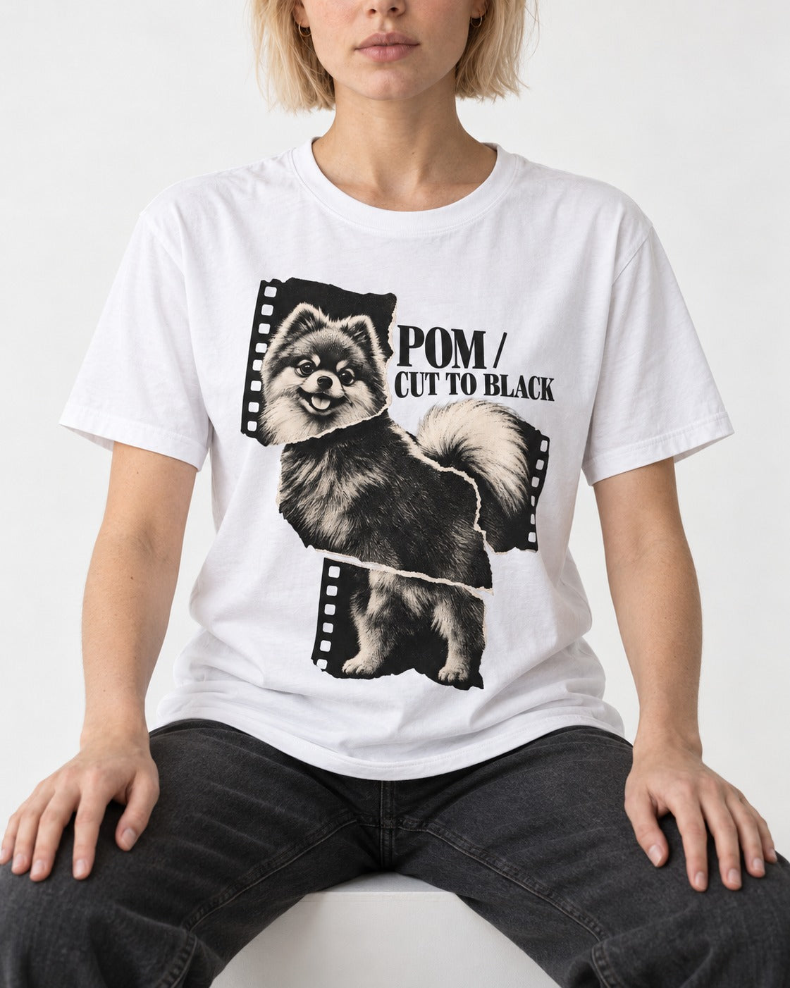 Pomeranian Cut to Black T-Shirt in White, worn by a seated model