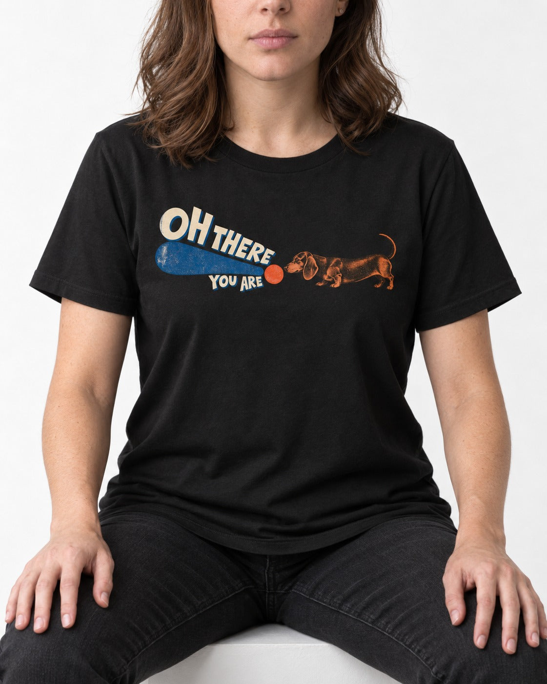 Dachshund Oh There You Are Ball Graphic T-Shirt in Black, worn by a seated model