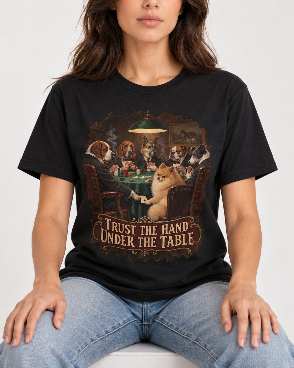 Pomeranian Trust the Hand Under the Table Poker Dogs Graphic T-Shirt in Black, worn by a seated model