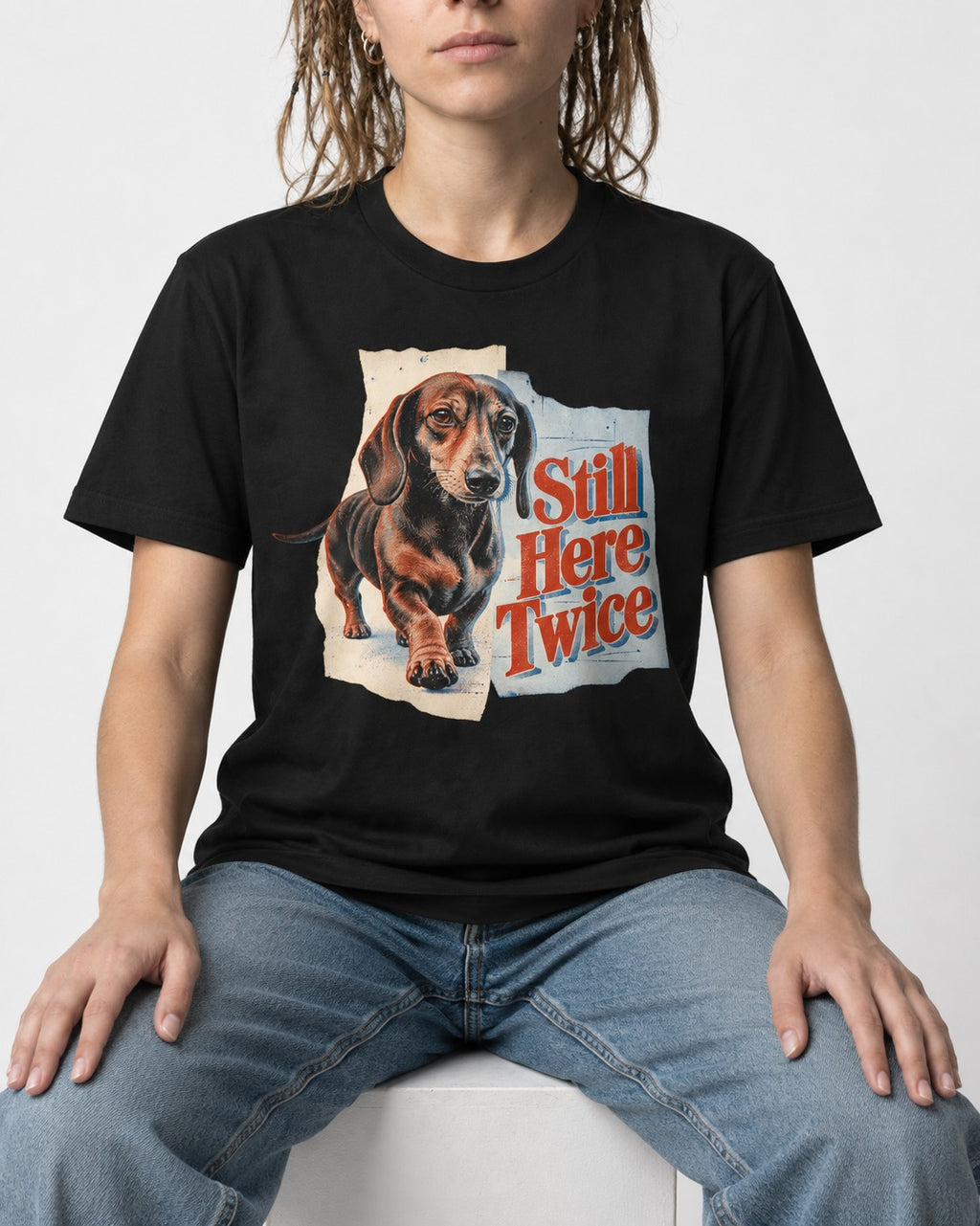 Dachshund Still Here Twice Torn Paper Graphic T-Shirt in Black, worn by a seated model