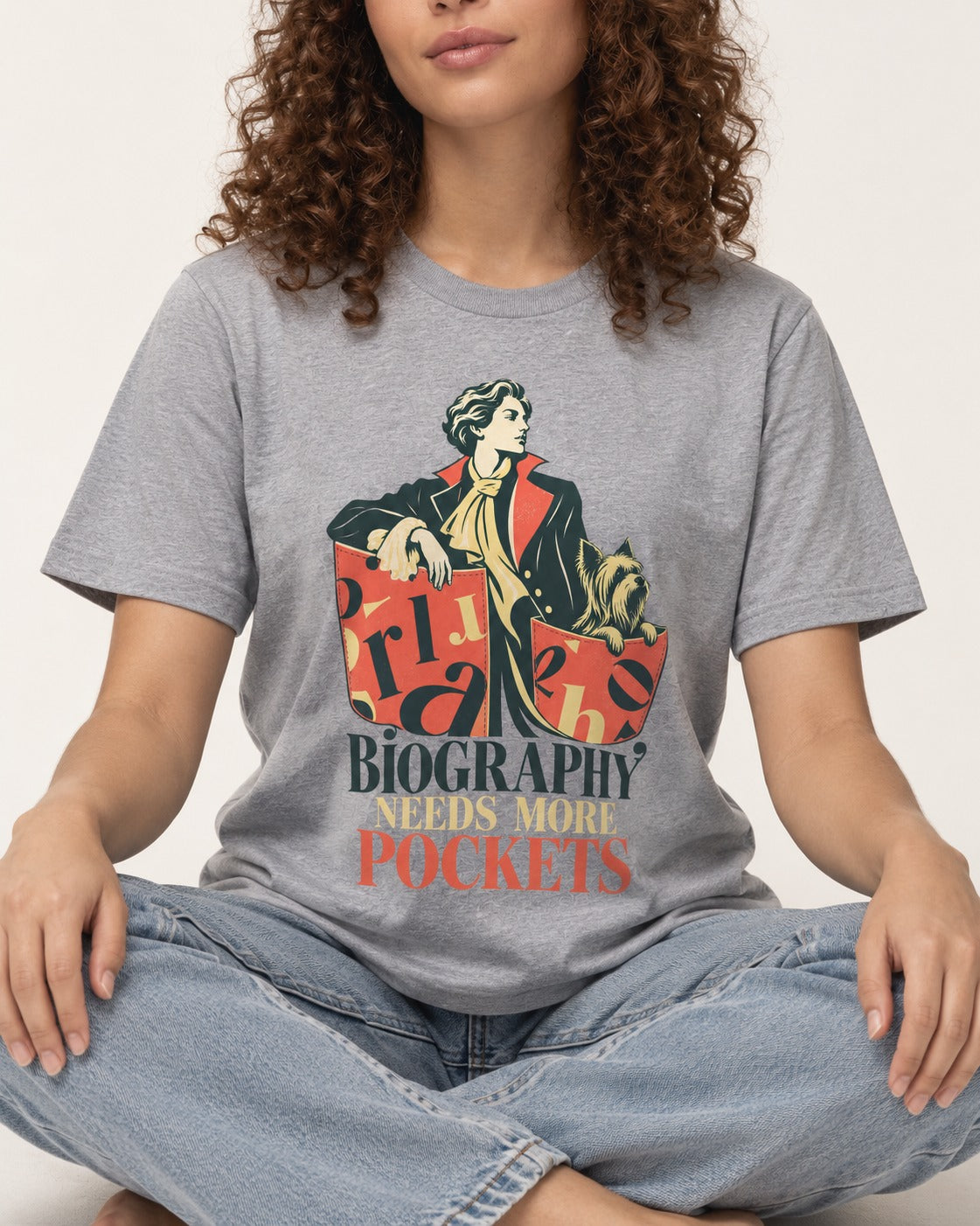 Yorkshire Terrier Biography Needs More Pockets Literary Portrait Graphic T-Shirt in Sport Grey, worn by a seated model