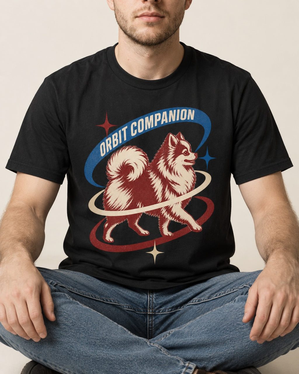 Pomeranian Orbit Companion Retro Space Graphic T-Shirt in Black, worn by a seated model