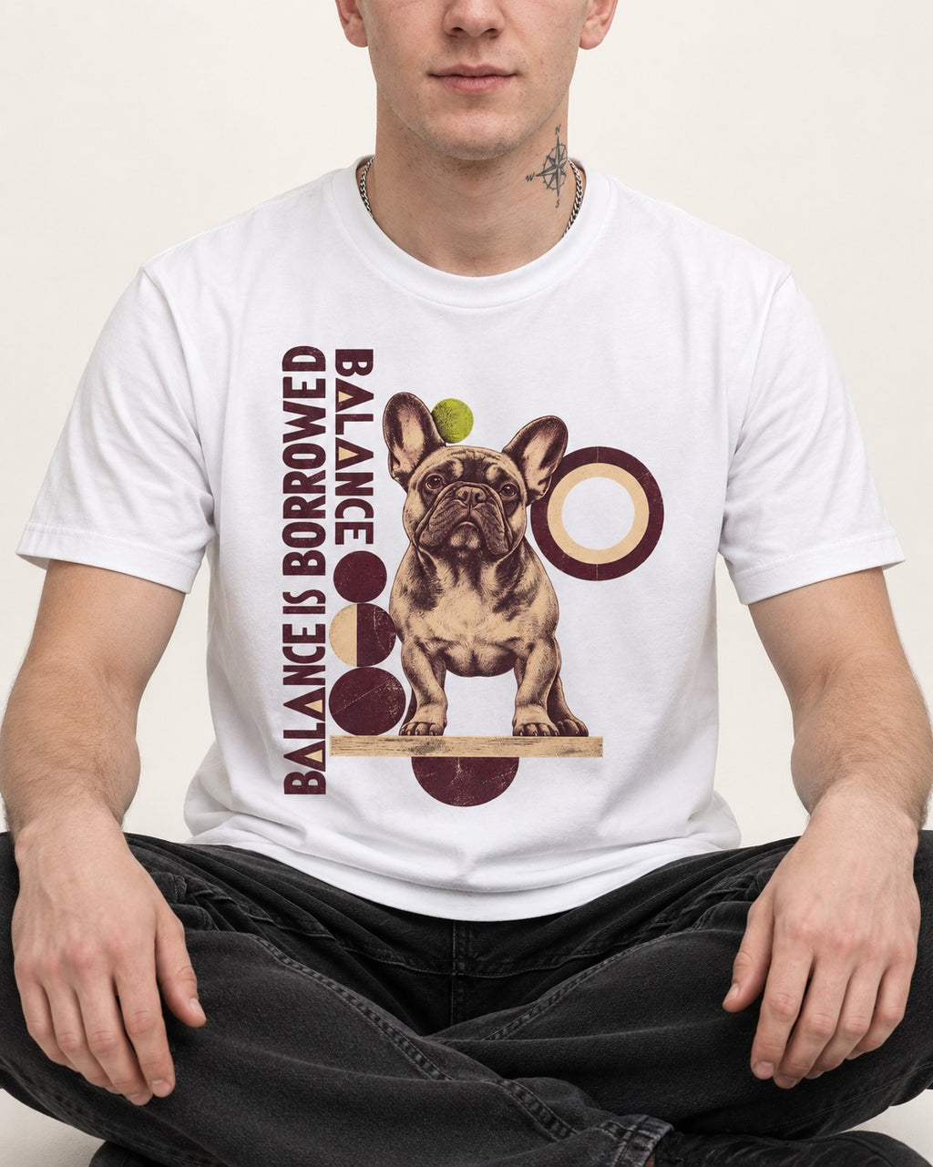 Frenchie's Balance Is Borrowed T-Shirt in White, worn by a seated model