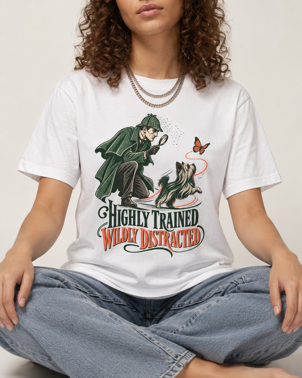 Highly Trained Wildly Distracted Yorkshire Terrier T-Shirt in White, worn by a seated model