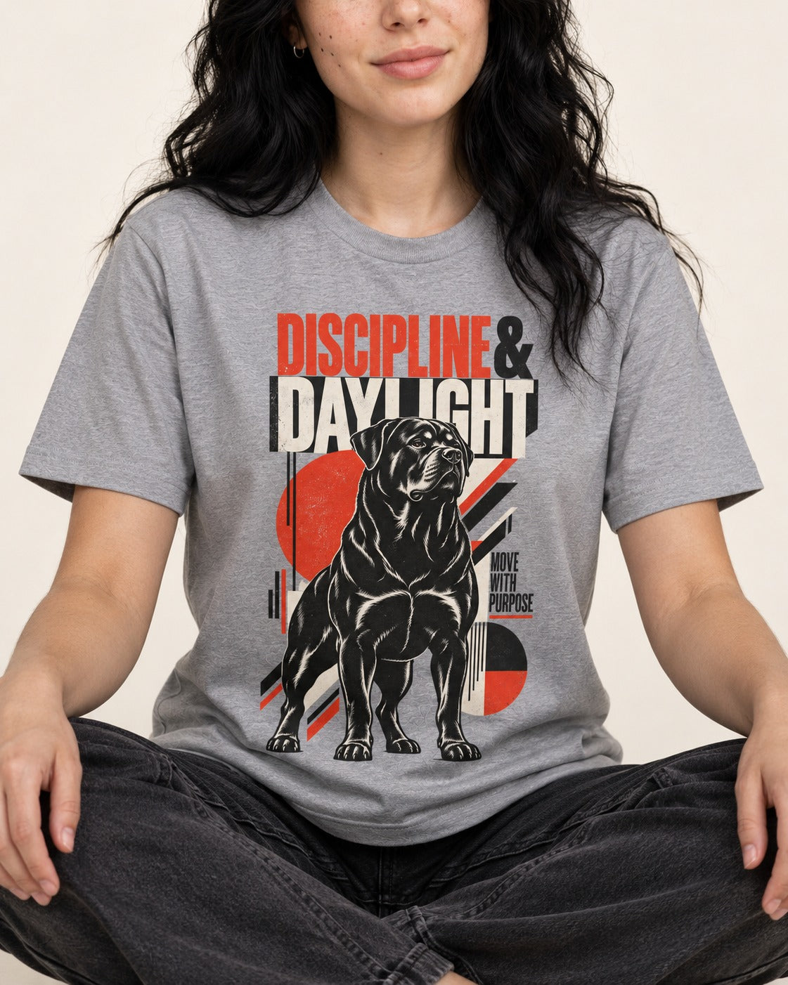 Discipline and Daylight Rottweiler Move With Purpose T-Shirt in Sport Grey, worn by a seated model