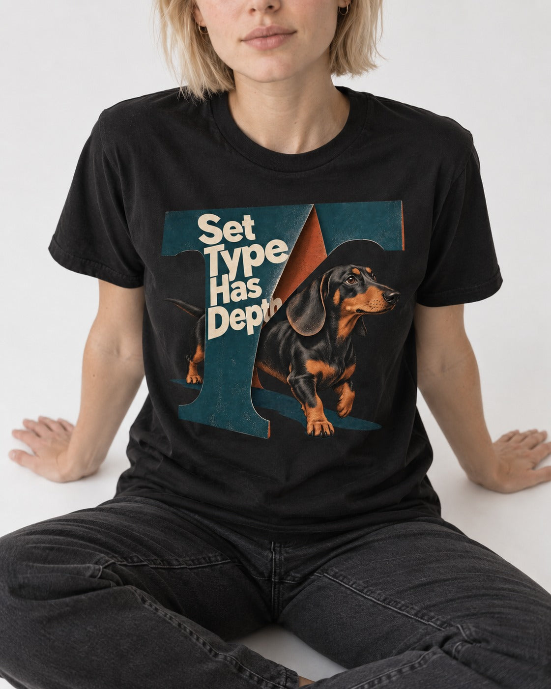 Dachshund Set Type Has Depth Folded Letter Graphic T-Shirt in Black, worn by a seated model