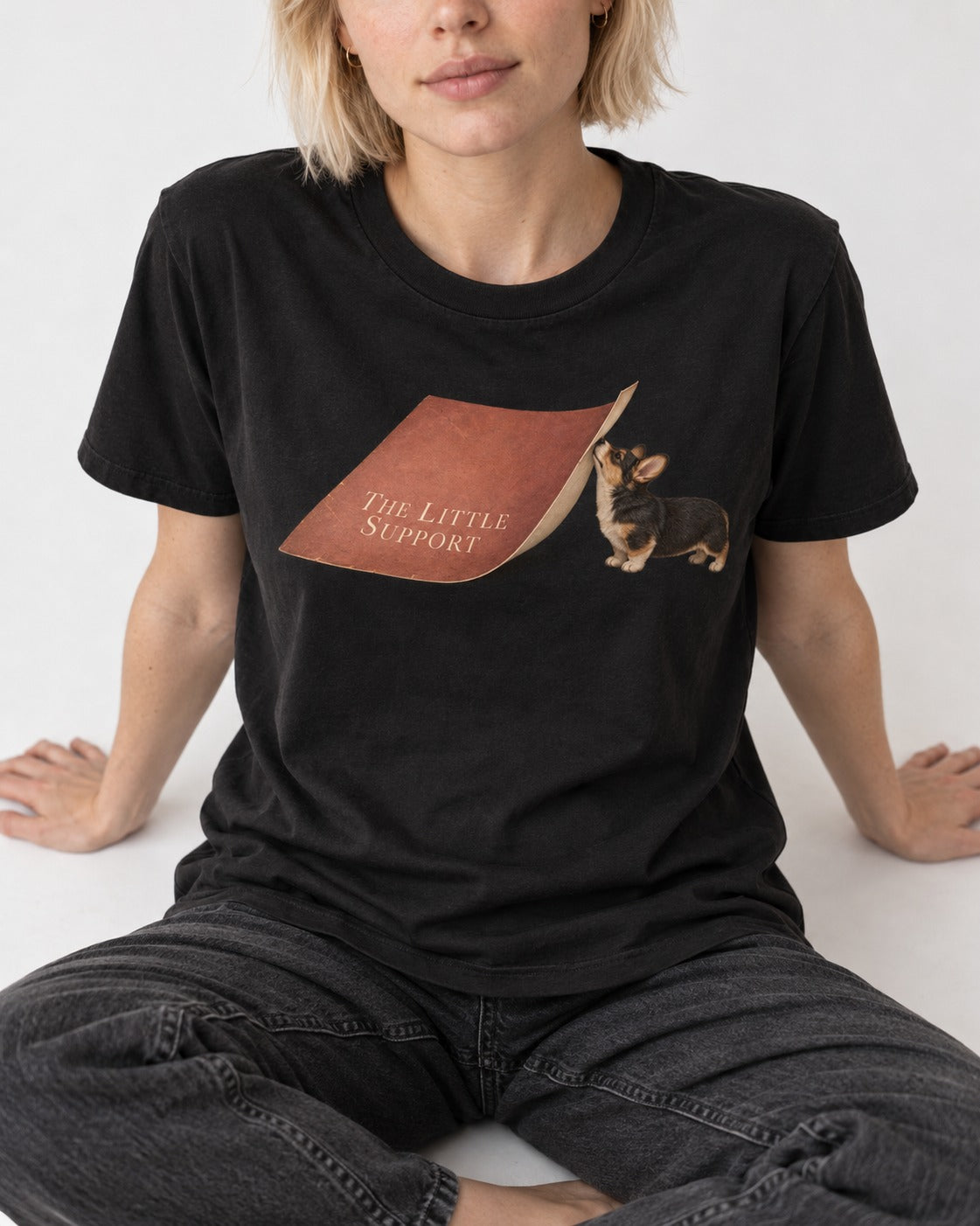 Corgi The Little Support Paper Graphic T-Shirt in Black, worn by a seated model