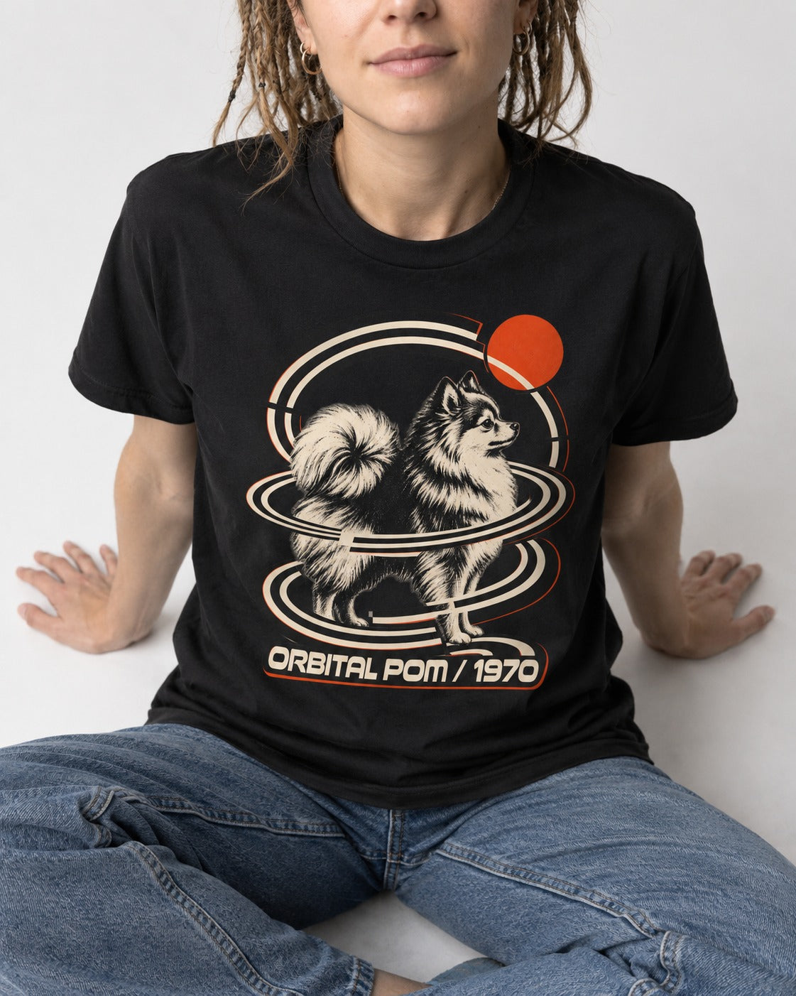 Pomeranian Orbital Pom 1970 Space Age Graphic T-Shirt in Black, worn by a seated model