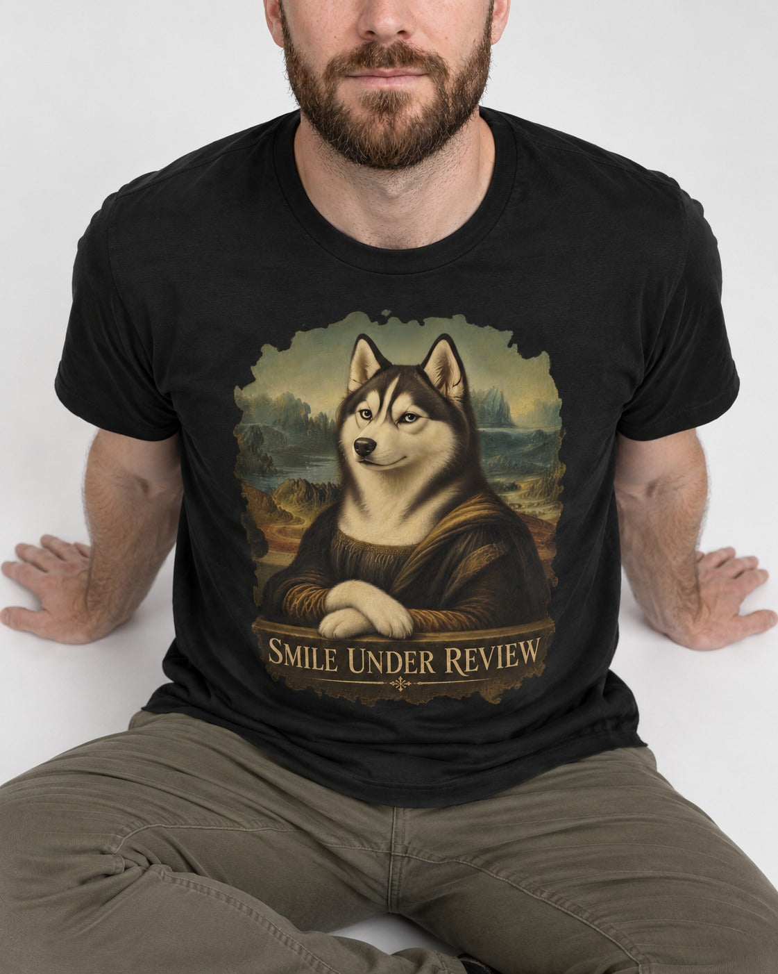 Husky Smile Under Review Renaissance Portrait Graphic T-Shirt in Black, worn by a seated model