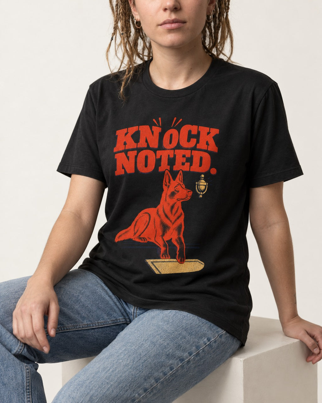 Knock Noted Door Knocker German Shepherd Dog Graphic T-Shirt in Black, worn by a seated model