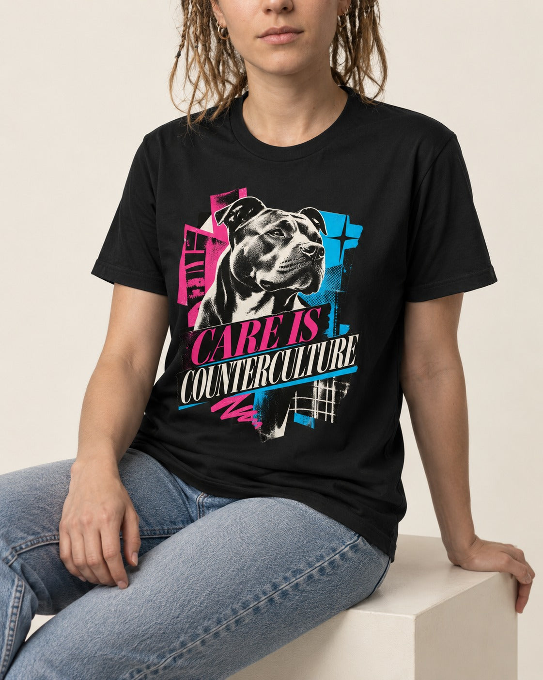 Pitbull Care Is Counterculture Neon Collage Portrait Graphic T-Shirt in Black, worn by a seated model