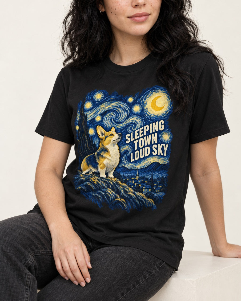 Corgi Sleeping Town Loud Sky Starry Night T-Shirt in Black, worn by a seated model
