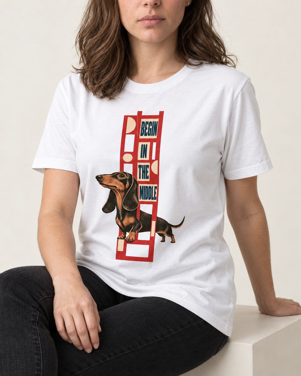 Dachshund Begins in the Middle T-Shirt in White, worn by a seated model