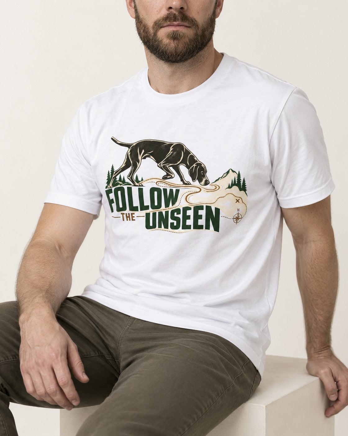 Follow the Unseen German Shorthaired Pointer T-Shirt in White, worn by a seated model