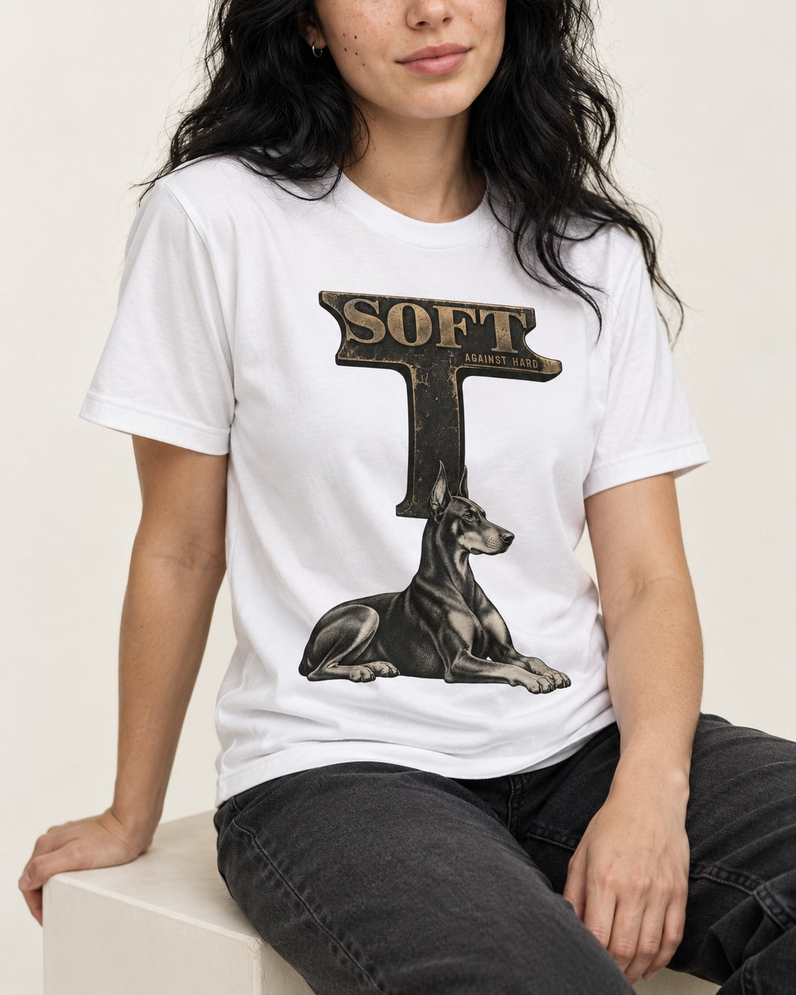Soft Against Hard Doberman T-Shirt in White, worn by a seated model