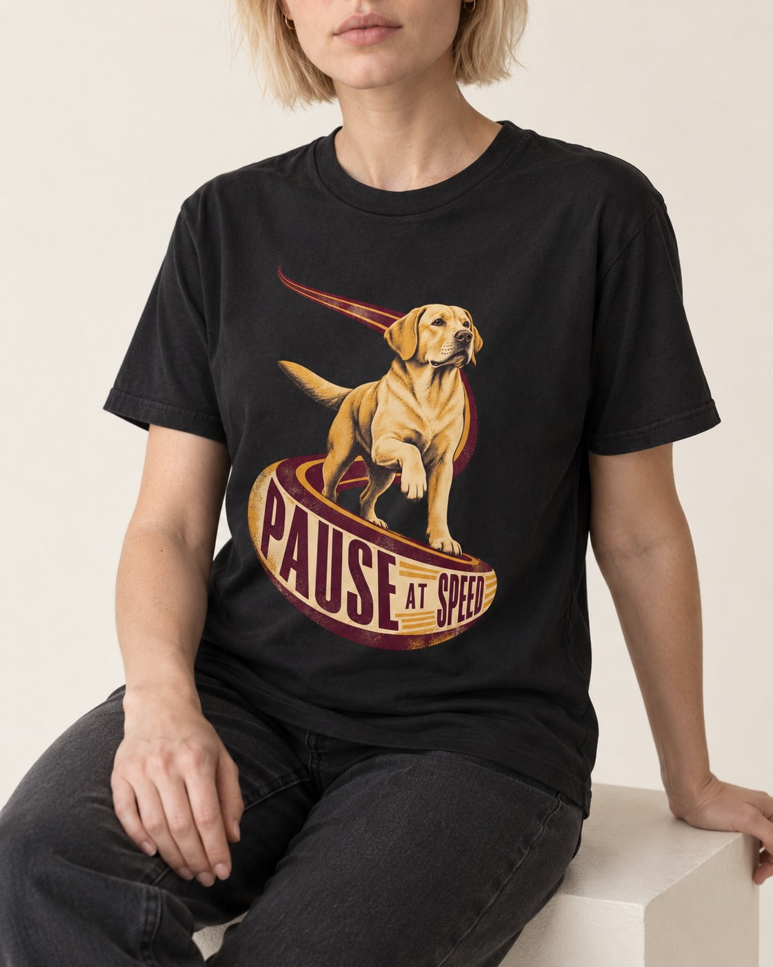 Labrador Retriever Pause at Speed Ribbon Graphic T-Shirt in Black, worn by a seated model