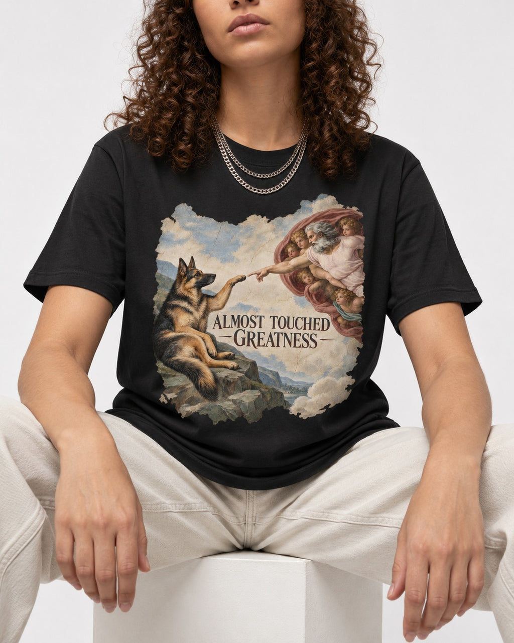 German Shepherd Dog Almost Touched Greatness Creation Parody T-Shirt in Black, worn by a seated model