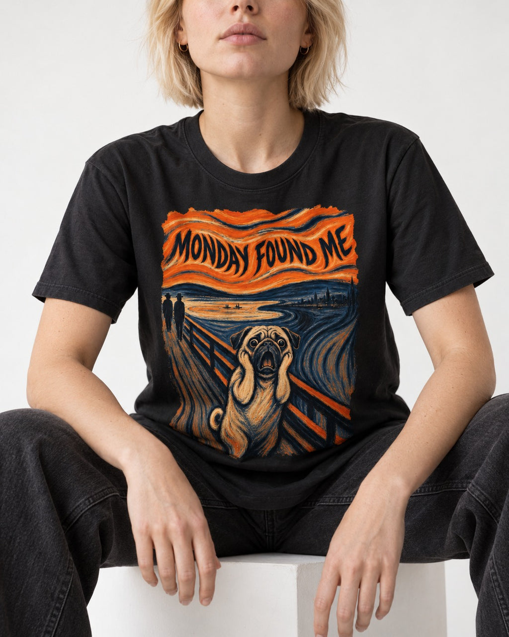 Pug Monday Found Me Scream Parody Graphic T-Shirt in Black, worn by a seated model