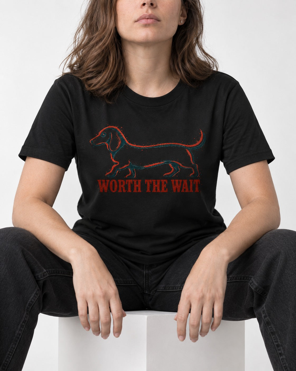 Dachshund Worth The Wait Distressed Outline Graphic T-Shirt in Black, worn by a seated model
