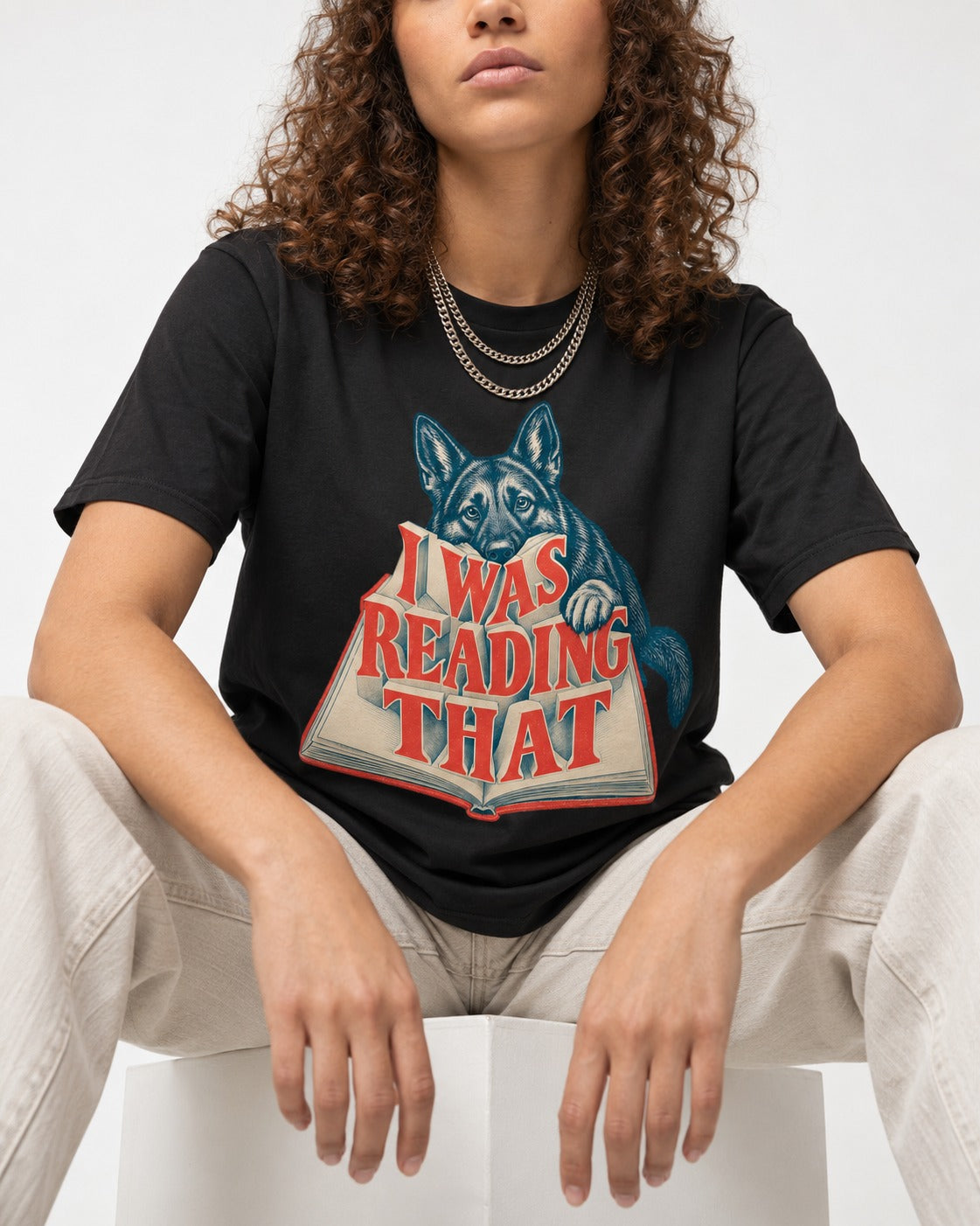 German Shepherd Dog I Was Reading That Open Book Graphic T-Shirt in Black, worn by a seated model