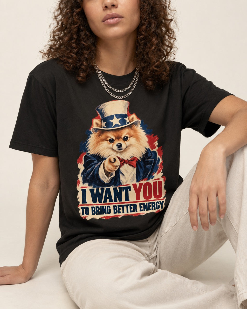 Pomeranian I Want You to Bring Better Energy Uncle Sam Graphic T-Shirt in Black, worn by a seated model