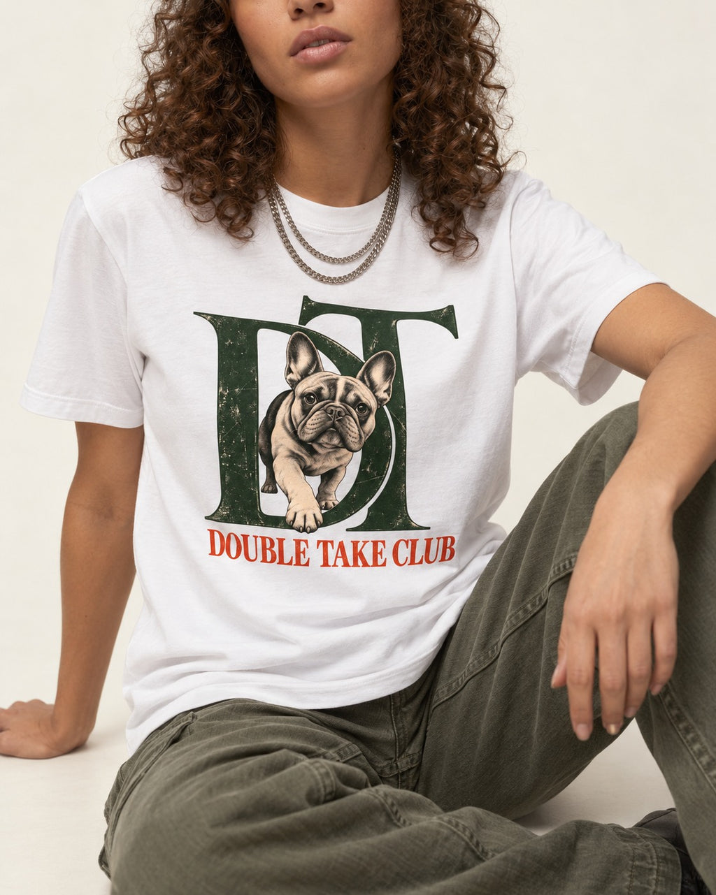 Frenchie Double Take Club T-Shirt in White, worn by a seated model