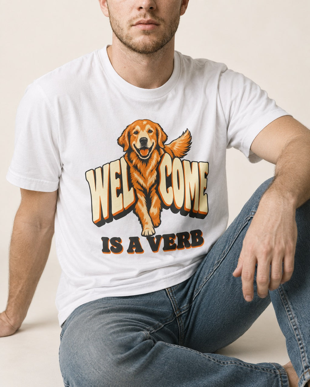 Golden Retriever Welcome Is a Verb T-Shirt in White, worn by a seated model