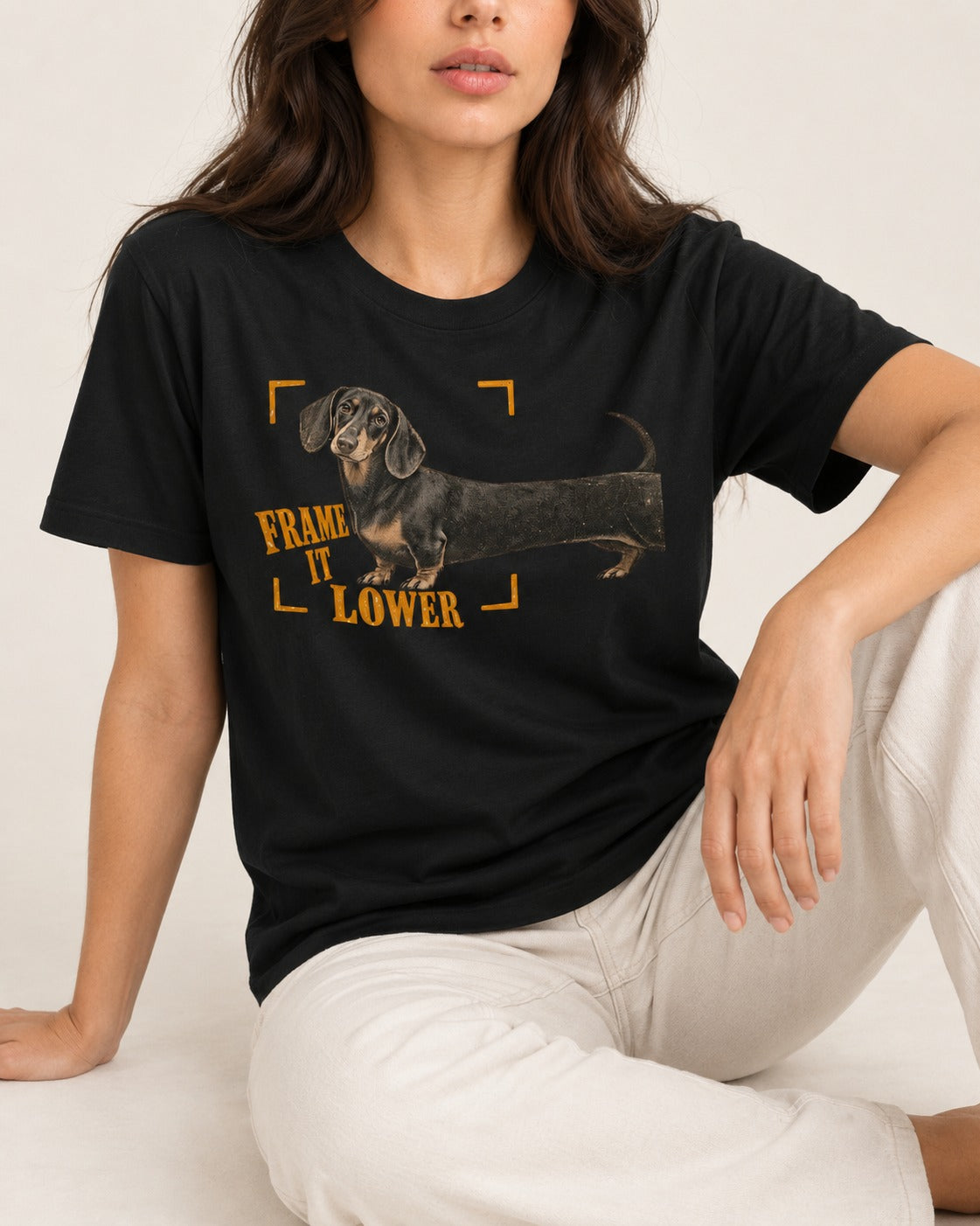 Dachshund Frame It Lower Viewfinder Graphic T-Shirt in Black, worn by a seated model