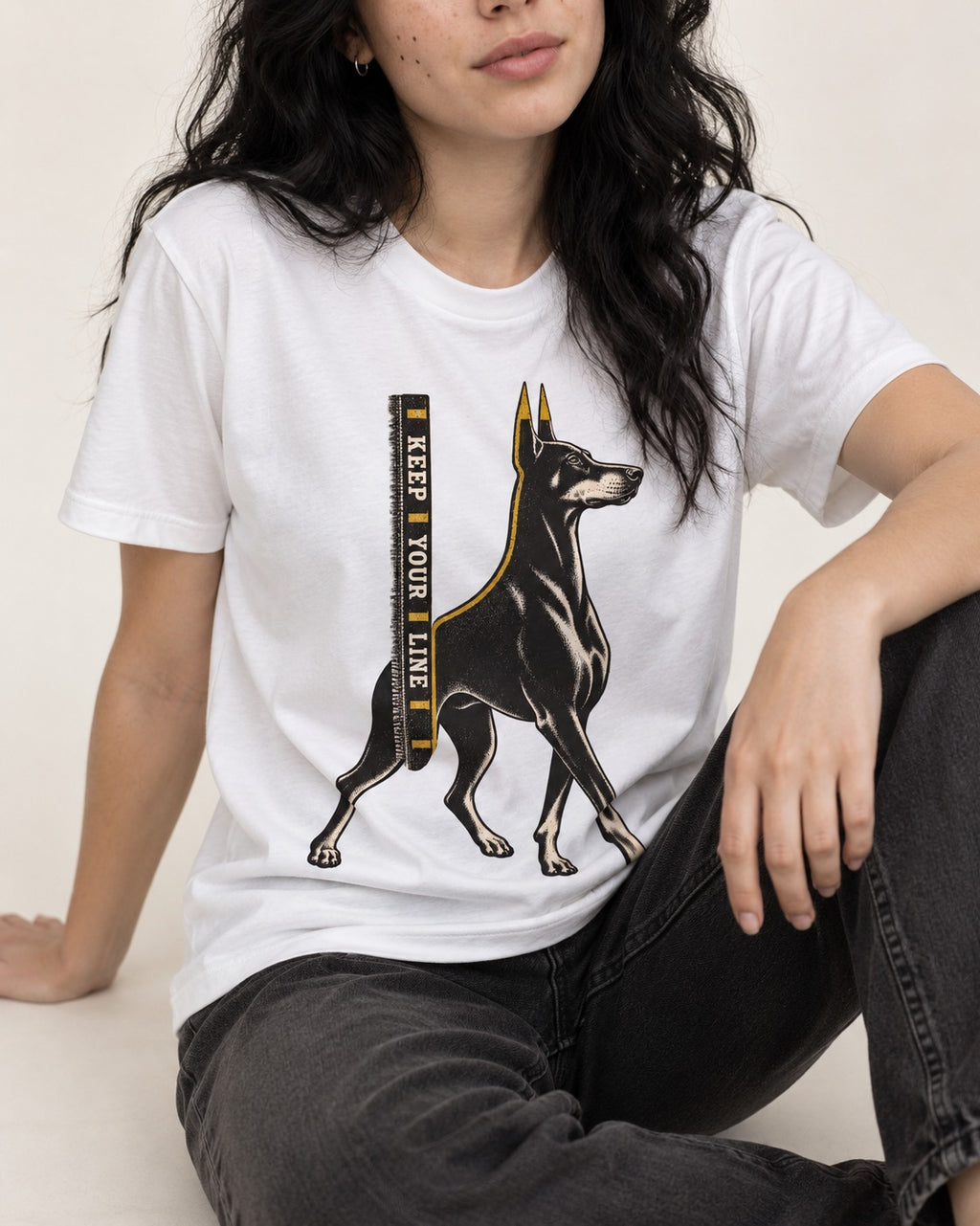 Keep Your Line Doberman T-Shirt in White, worn by a seated model