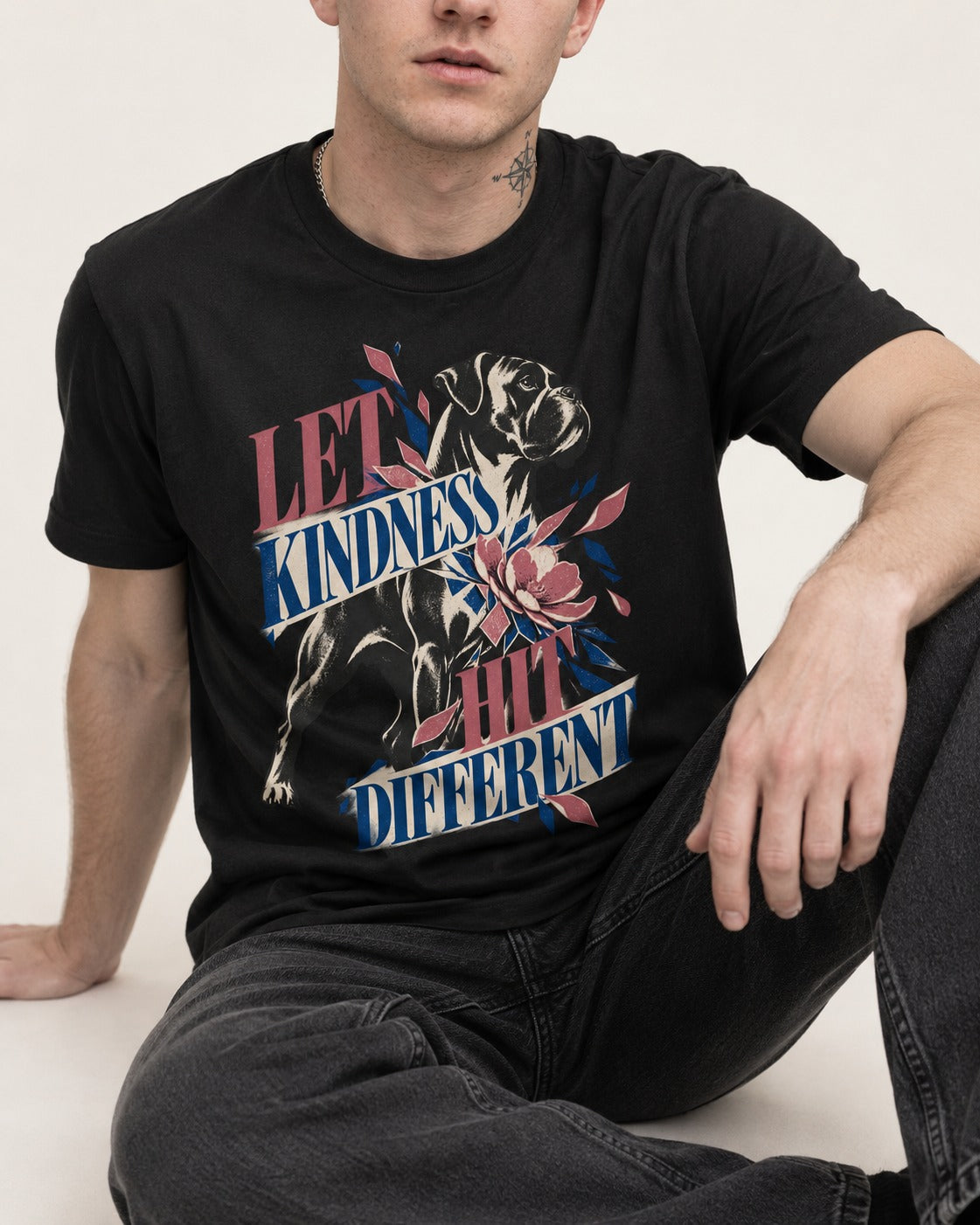 Let Kindness Hit Different Boxer Floral Collage T-Shirt in Black, worn by a seated model