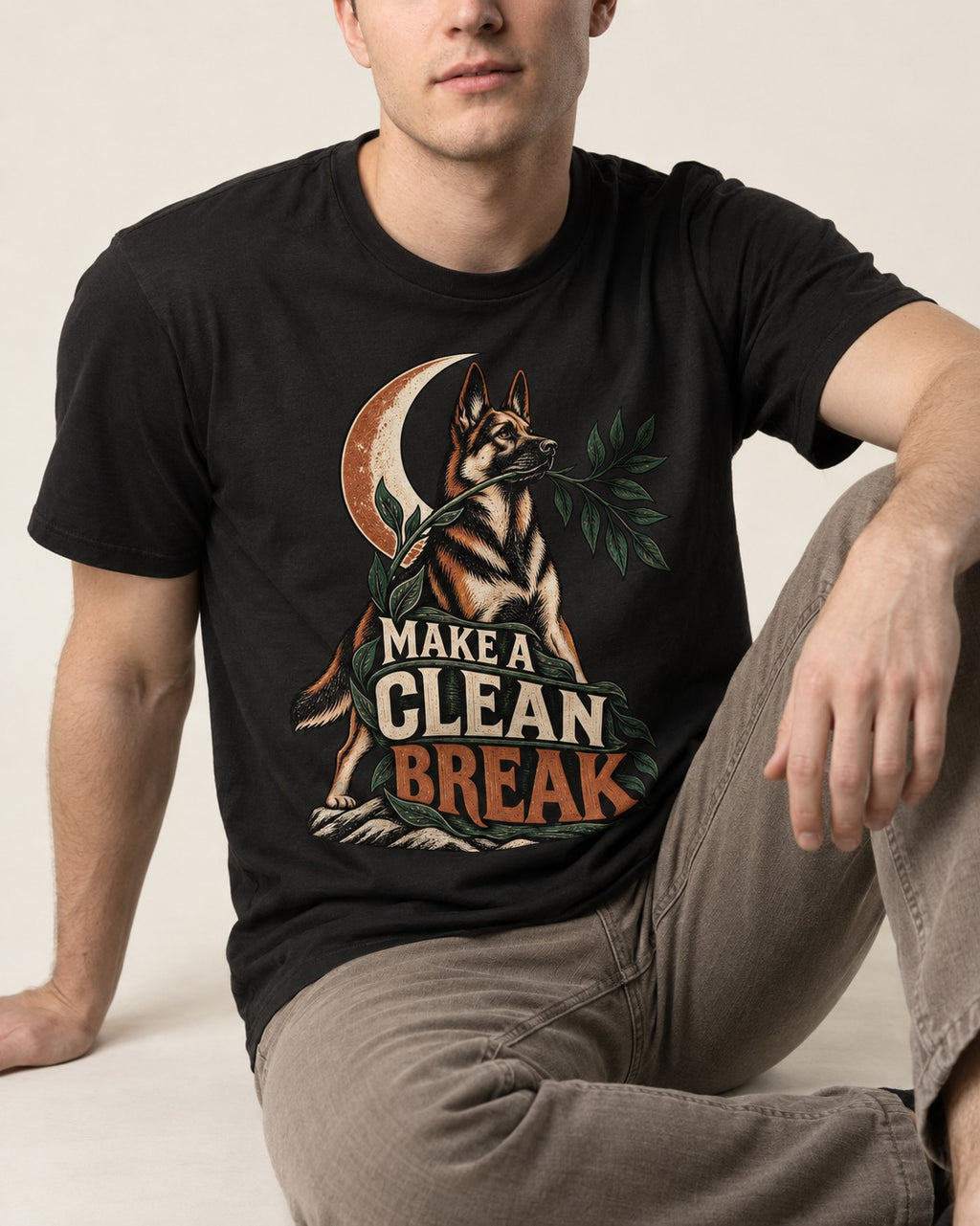 Make A Clean Break Crescent Botanical German Shepherd Dog Graphic T-Shirt in Black, worn by a seated model